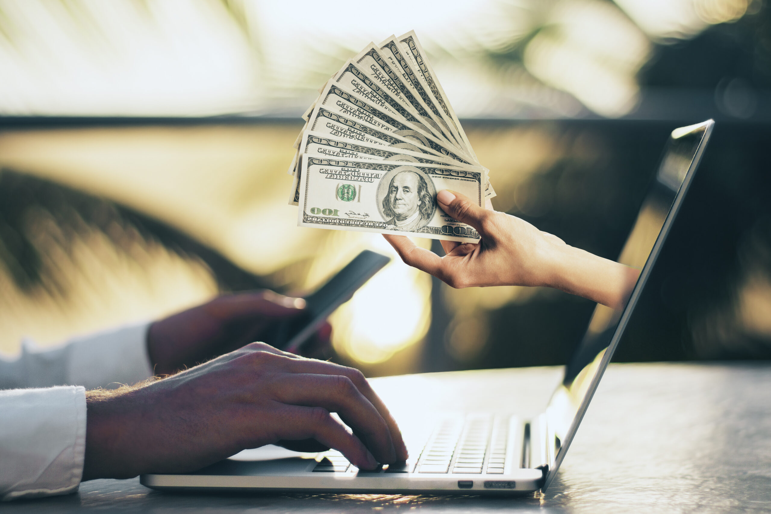 hand-with-dollars-sticking-out-of-laptop-screen-c-2026-01-11-08-45-33-utc (1)