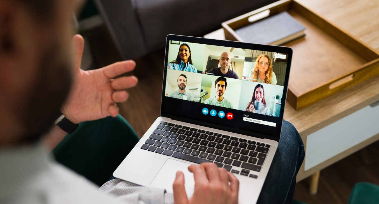 Rear view of a man having a work meeting online. Adult man talking with co-workers during a video call on his laptop